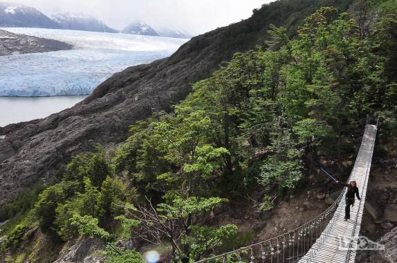 Sobre uma enorme ponte pênsil, a Ana aponta para o glaciar Grey, no parque nacional Torres del Paine, no sul do Chile